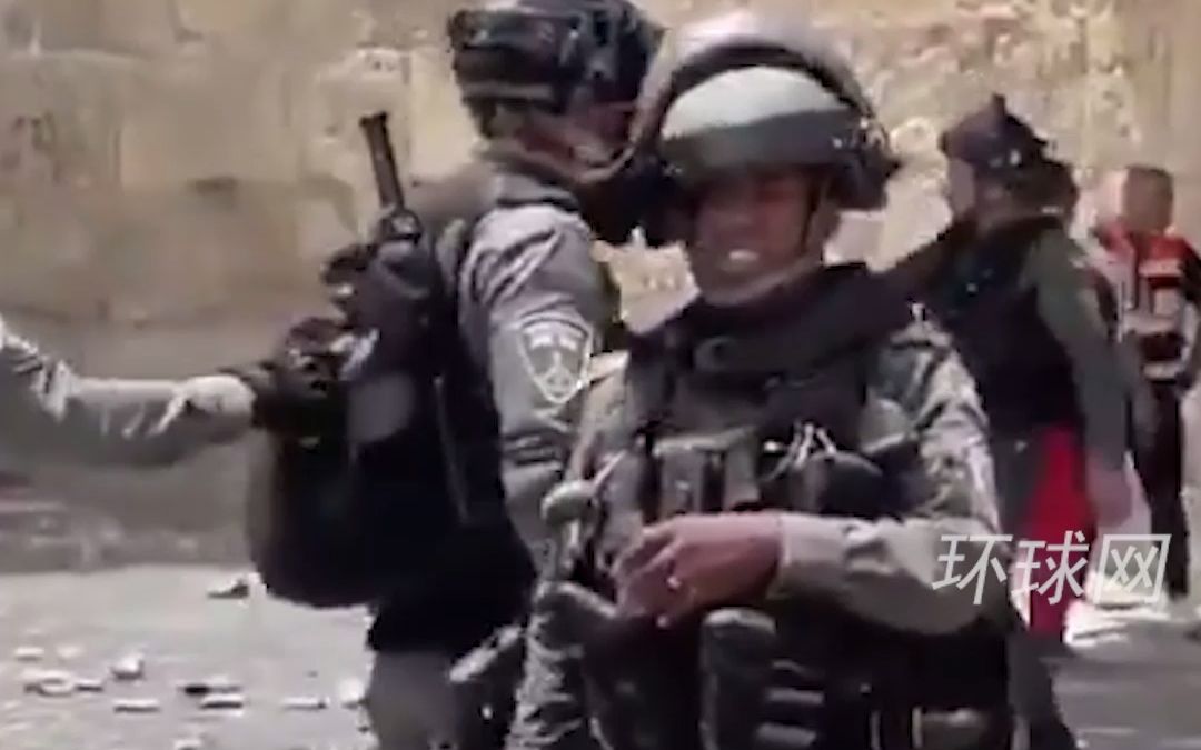 以色列士兵正准备朝人群投掷武器，看到记者镜头后立刻收手