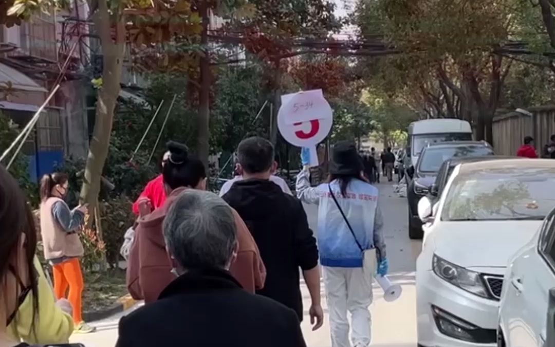 上海运动会式核酸检测入场。工作人员举牌，居民按楼栋排队采样。