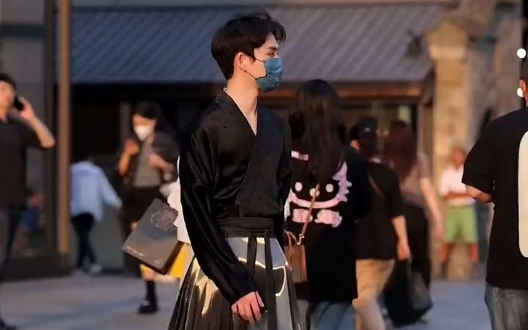 男子穿着“浮光”马面裙走在街头，闪闪发光引众人注视