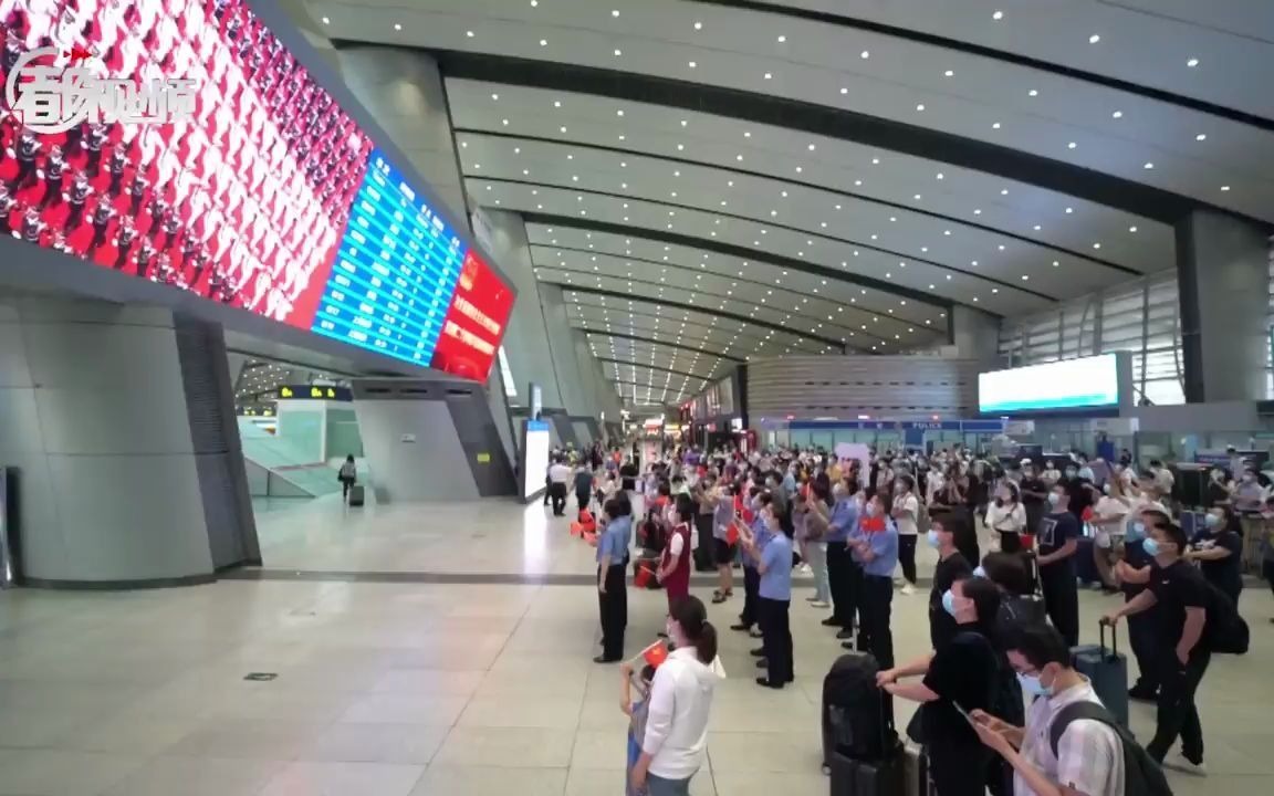 北京南站，旅客在大屏幕前驻足观看大会盛况