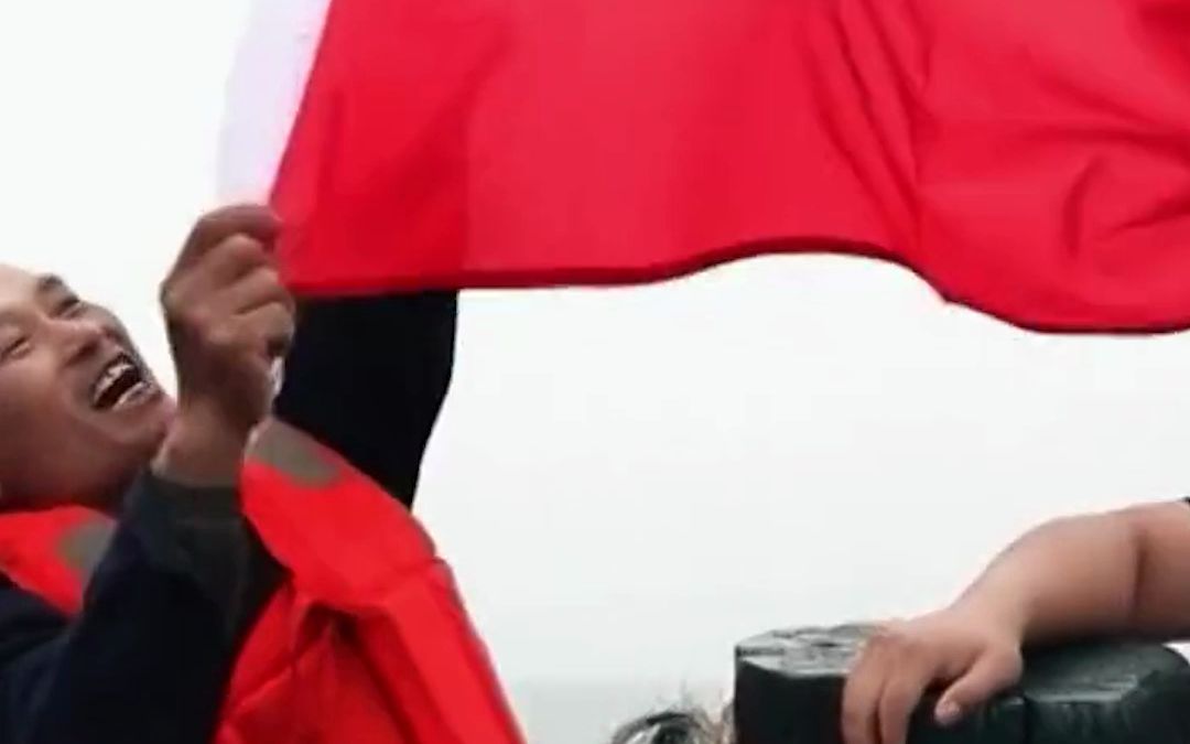 难掩激动！青岛渔民打渔归来，偶遇山东舰，众人高举国旗唱《歌唱祖国》。