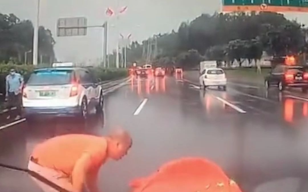 国旗飘路在地 司机停车捡起国旗 后方车辆无人鸣笛催促